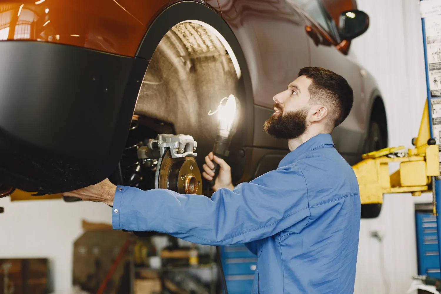 Mechanic inspecting a vehicle's brake assembly in an automotive repair shop